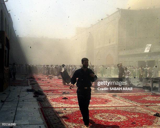 Iraqi men flee following an explosion 29 August 2003, inside the Shrine of Imam Ali, one of Shiite Islam's holiest shrines in the central city of...