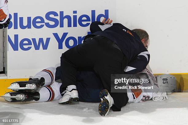 Head medical trainer Ken Lowe tends to Liam Reddox of the Edmonton Oilers after he was injured from a third period check into the boards by Clarke...
