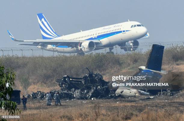 An airplane takes off at the international airport in Kathmandu on March 13 near the wreckage of a US-Bangla Airlines plane that crashed on March 12....