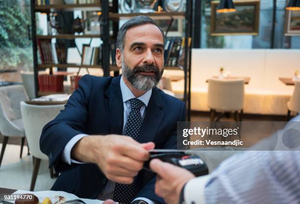 business people have a meal in hotel restaurant - paying for dinner imagens e fotografias de stock