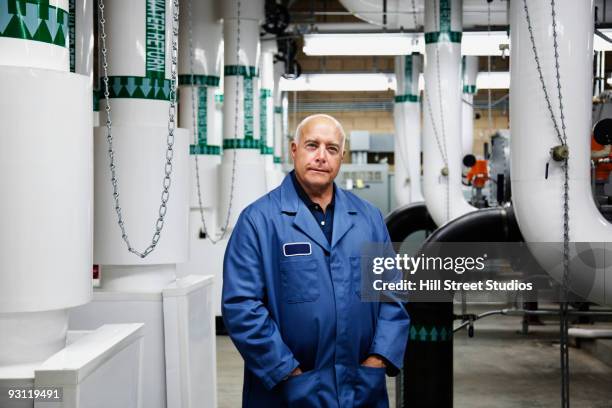 confident technician standing in industrial plant - industrial laborer foto e immagini stock