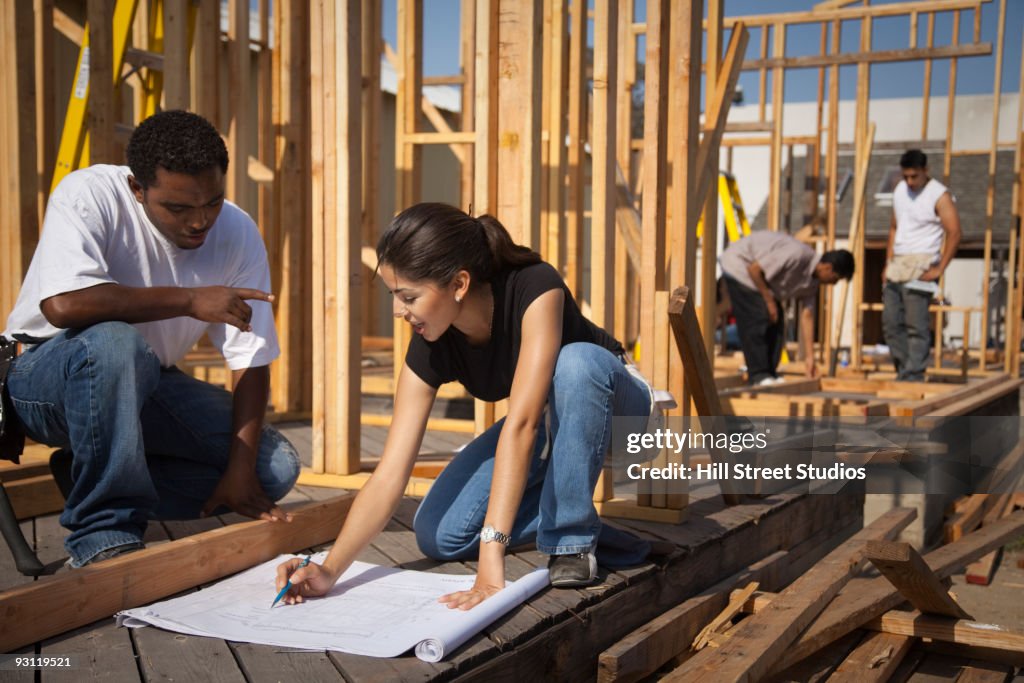 Man and woman reviewing blueprints at construction site
