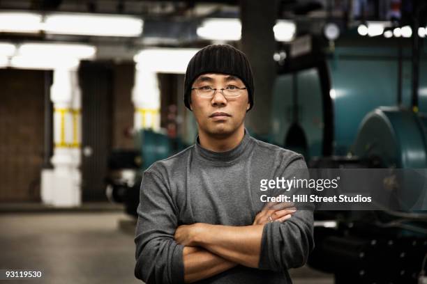 serious chinese man with arms crossed in industrial plant - industrial laborer foto e immagini stock