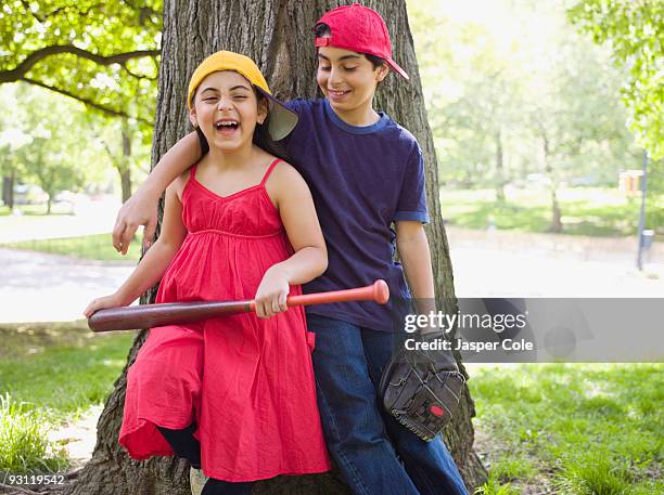 smiling mixed race brother and sister holding baseball bat and mitt - girl baseball cap stock pictures, royalty-free photos & images