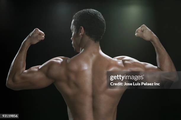 mixed race man flexing biceps - mixed race man standing studio stockfoto's en -beelden