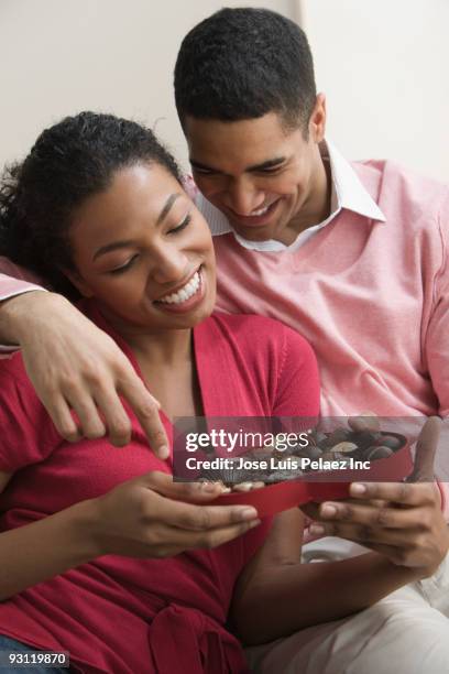 couple looking at chocolates in heart-shaped box - couple chocolate - fotografias e filmes do acervo