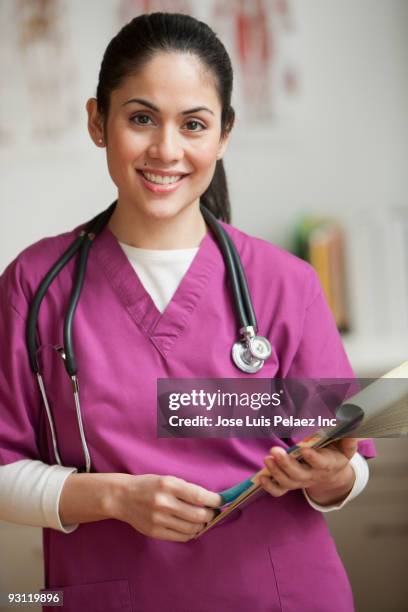 smiling mixed race nurse holding paperwork - haitian ethnicity fotografías e imágenes de stock