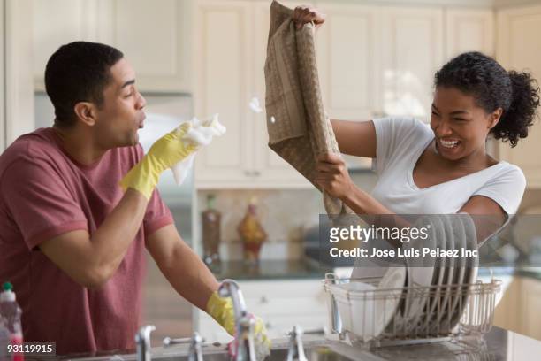 playful couple washing dishes - housework humour stock pictures, royalty-free photos & images