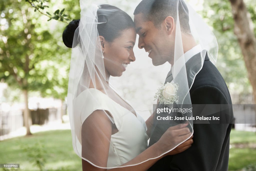 Bride and groom hugging under veil