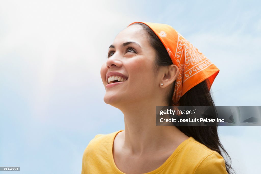 Smiling mixed race woman wearing bandana and looking up at sky