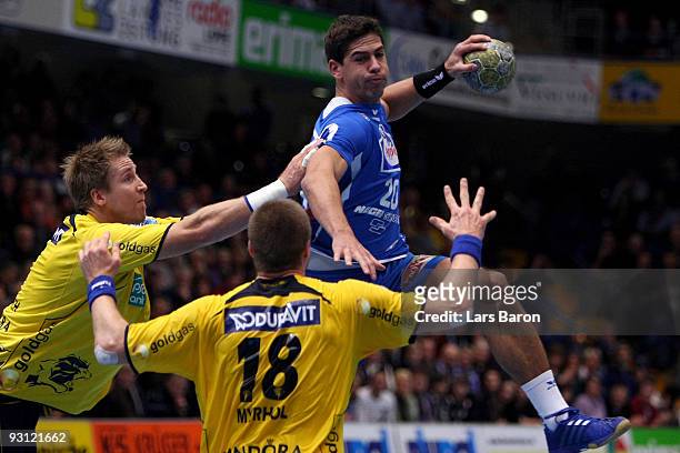 Rolf Hermann of Lemgo is challenged by Oliver Roggisch and Bjarte Myrhol of Rhein Neckar during the Handball Bundesliga match between TBV Lemgo and...