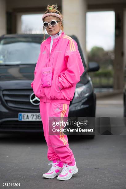 Guest poses wearing a Gosha Rubchinskiy X Adidas pink tracksuit and Chanel sneakers after the Miu Miu show at the Palais de Iena during Paris Fashion...