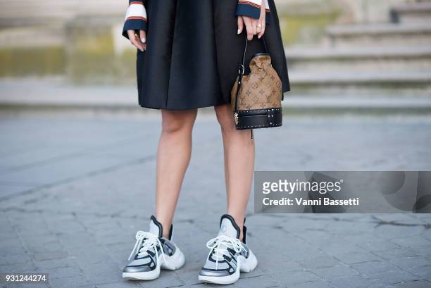 Guest poses wearing Louis Vuitton sneakers before the Louis Vuitton show at the Pyramide du Louvre during Paris Fashion Week Womenswear FW 18/19 on...