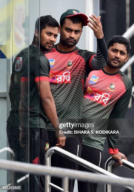Bangladesh cricketers Imrul Kayes , Sabbir Rahman and Tamim Iqbal look on from the dressing room after rain delayed a training session at the R....