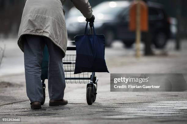 An old man is walking on a sidewalk with a walking frame on March 06, 2018 in Berlin, Germany.