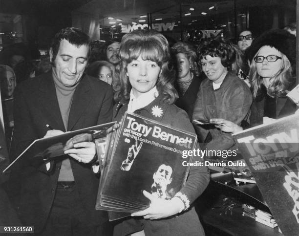 American singer Tony Bennett autographs a copy of his LP 'Get Happy with the London Philharmonic Orchestra' for a fan at Chappells Music Centre in...