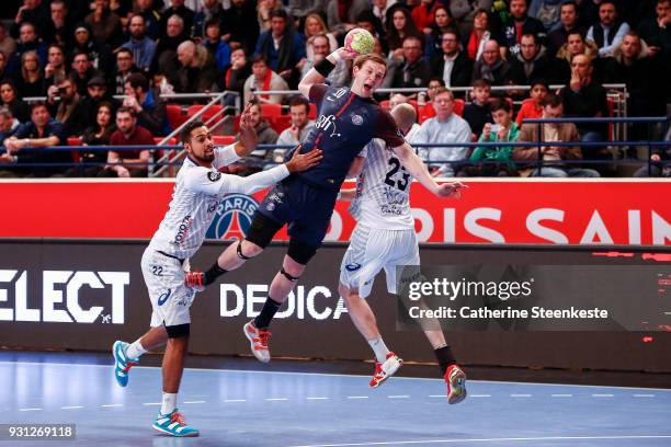 Sander Sagosen of Paris Saint Germain is shooting the ball against Melvyn Richardson of Montpellier Handball and Vid Kavticnik of Montpellier...