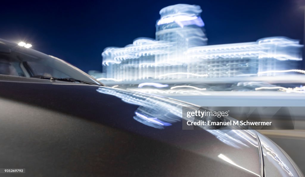Driving car in Dubai while night with illuminated blurred building in background