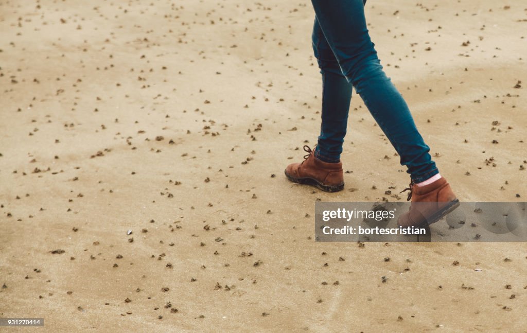 Low Section Of Woman Walking On Sand