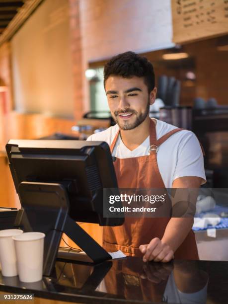 young sales clerk working at a bakery adding orders on the system looking happy - checkout register stock pictures, royalty-free photos & images