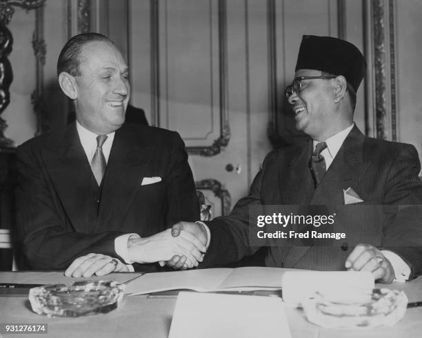 British Conservative politician Alan Lennox-Boyd , the Secretary of State for the Colonies, shakes hands with Tunku Abdul Rahman , the Chief Minister...