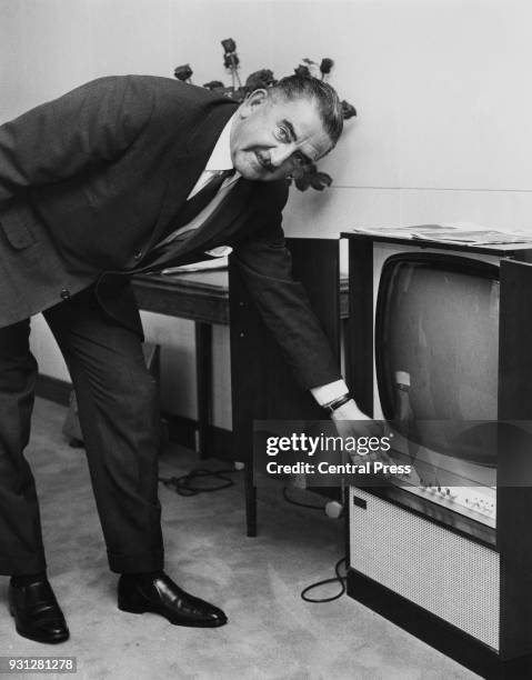 Herbert Bowden , the new chairman of the Independent Television Authority, turns on a television at the organisation's headquarters in Brompton Road,...