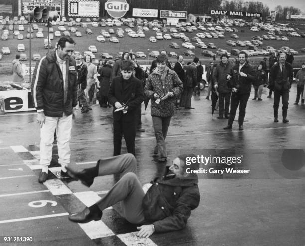 Australian racing driver Jack Brabham watches car maker John Cooper perform a forward roll on the track at Brands Hatch, UK, making good on his...