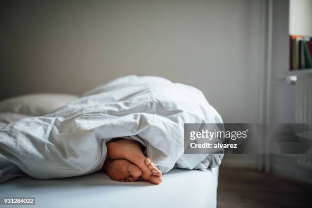 low section of young woman sleeping in bed - duvet stock pictures, royalty-free photos & images