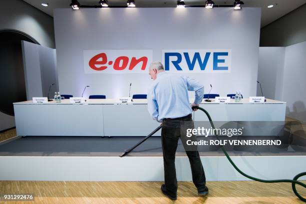 Man cleans the carpet prior to a joint press conference of German energy supplier RWE and German utility company EON on March 13, 2018 in Essen,...