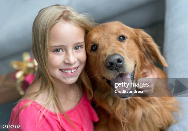 beautiful dog and little girl at home both looking at the camera and girl embracing the dog while smiling - cheek tongue stock pictures, royalty-free photos & images