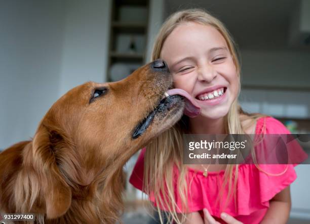 cheerful little girl and her pet licking her cheek looking very happy - cheek tongue stock pictures, royalty-free photos & images