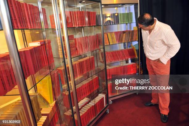 Un homme regarde la collection complète des guides Michelin avant la vente aux enchères de la collection d'objets Michelin d'Alain Morel à Royat près...