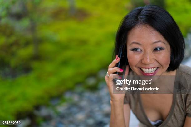 vooraanzicht van vrouw praten op mobiele telefoon in zen tuin van chion-ji tempel in kyoto, japan - kumikomini stockfoto's en -beelden