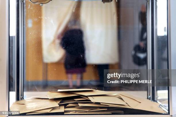 Une personne choisit son bulletin de vote dans l'isoloir le 20 mars 2011 dans un bureau de vote de la commune de Mardore , lors du premier tour des...