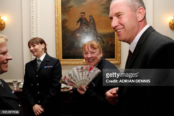Police officers react as they attend a reception for the winners of The Met Excellence Awards at Kensington Palace in London on March 13, 2018. The...