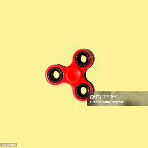 red spinner on a pale yellow background - gegengift stock-fotos und bilder