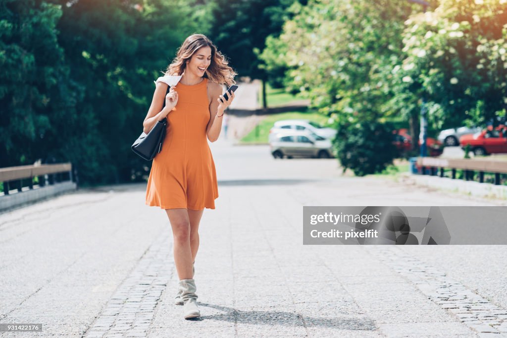 Menina bonita andando e mensagens de texto ao ar livre