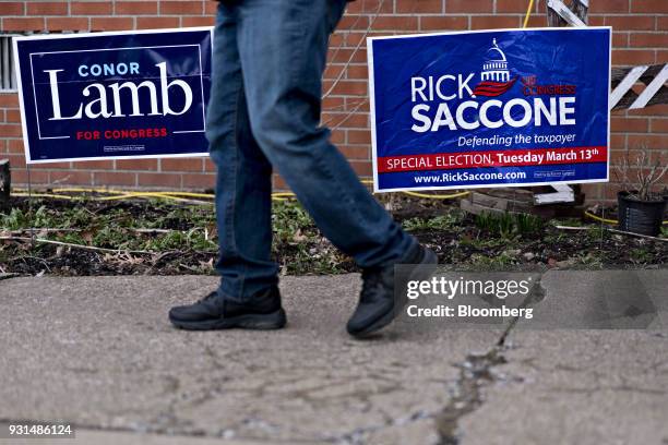 Resident walks past campaign signs for Conor Lamb, Democratic candidate for the U.S. House of Representatives, and Rick Saccone, Republican candidate...