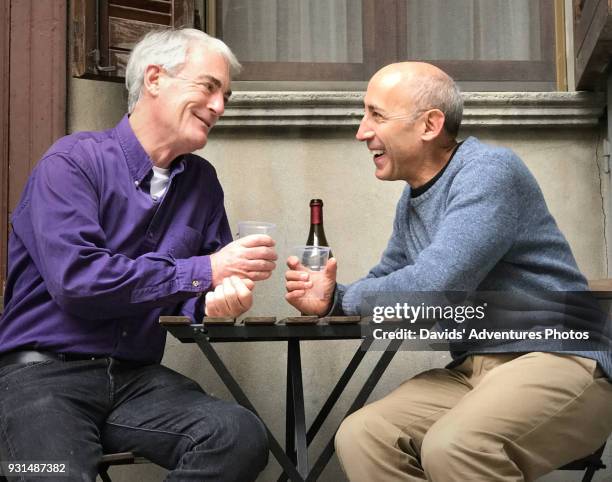 older gay couple or friends on vacation drinking wine outside at small table on sunny afternoon - bar tender photos et images de collection