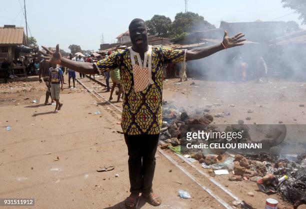 Demonstrator shouts as he stands beside a burning barricade on a street in Conakry on March 13 which was erected by demonstrators during a protest...