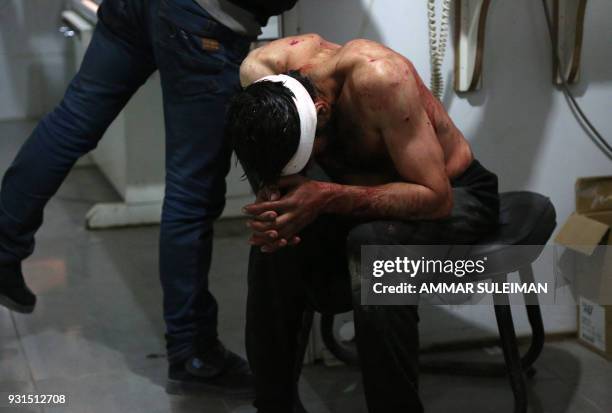 Wounded Syrian man waits to receive treatment at a make shift hospital following government bombardment in Kafr Batna in the rebel-held enclave of...