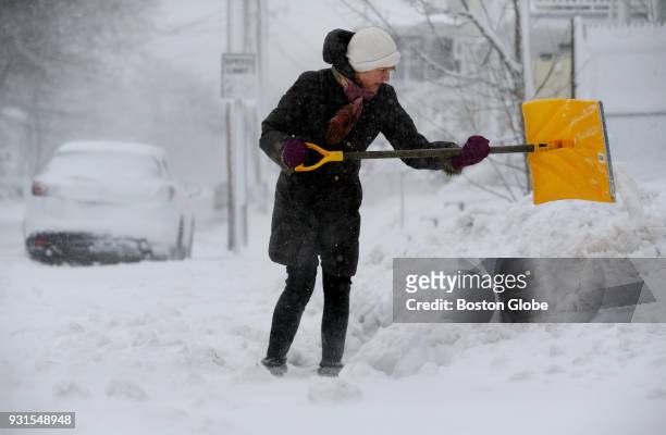 Eileen Paris clears snow from the sidewalk outside her home in Plymouth, MA during the third nor'easter storm to hit the region in two weeks on March...