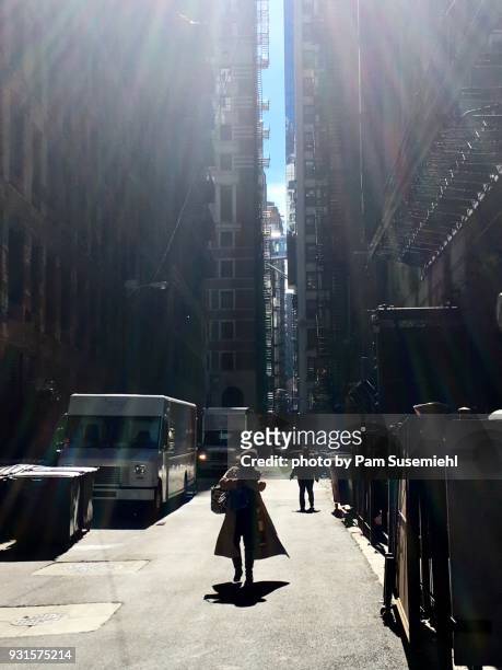 woman in silhouette walking through downtown chicago alley on blustery winter's day - chicago lifestyle stock pictures, royalty-free photos & images