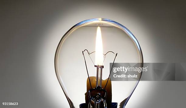 lampadina e fiamma della candela - luce elettrica foto e immagini stock