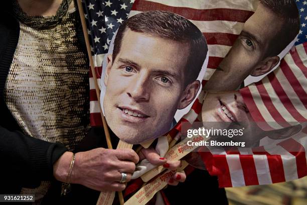 An attendee holds American flags and the portrait of Conor Lamb, Democratic candidate for the U.S. House of Representatives, during an election night...