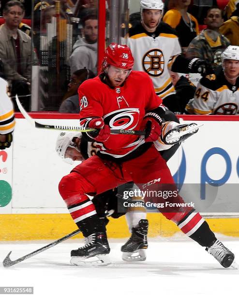 Elias Lindholm of the Carolina Hurricanes and Riley Nash of the Boston Bruins collide during an NHL game on March 13, 2018 at PNC Arena in Raleigh,...