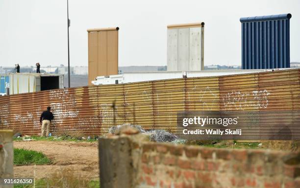 Federal Policeman stands on the Mexico border side as U.S. Snipers observe next to prototypes of the proposed border wall before President Trump's...