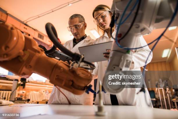 hieronder de mening van wetenschappers samenwerken tijdens het werken aan robotarm in laboratorium. - man robot stockfoto's en -beelden