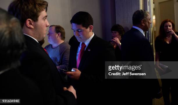 Campaign volunteer Michael Guido, center, checks early election results on his phone at an Election Night event for GOP PA Congressional Candidate...