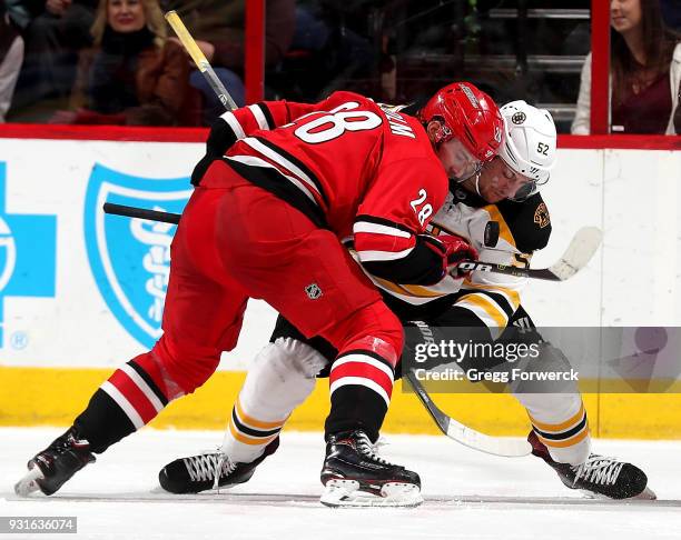 Elias Lindholm of the Carolina Hurricanes and Sean Kuraly of the Boston Bruins battle in the faceoff during an NHL game on March 13, 2018 at PNC...